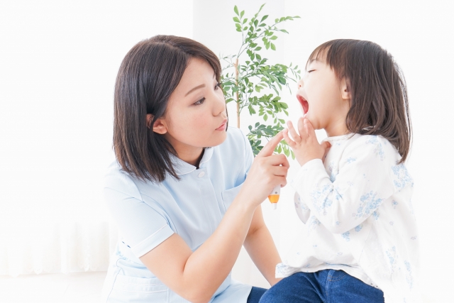 歯科衛生士が女の子の口の中を見ている